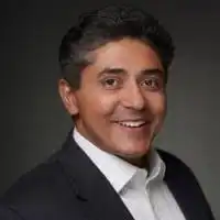 Dharmang Shelat, a smiling dark-haired man in a dark suit jacket and white shirt