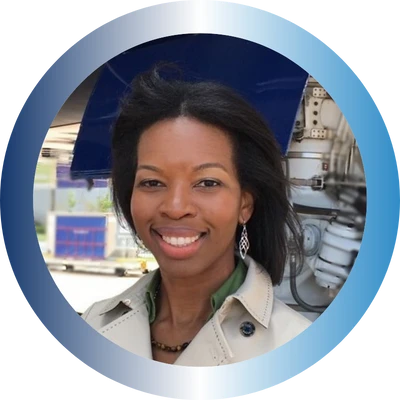 Kandyss Watson, a smiling woman with shoulder-length dark hair in a beige trench coat, framed in a blue circle